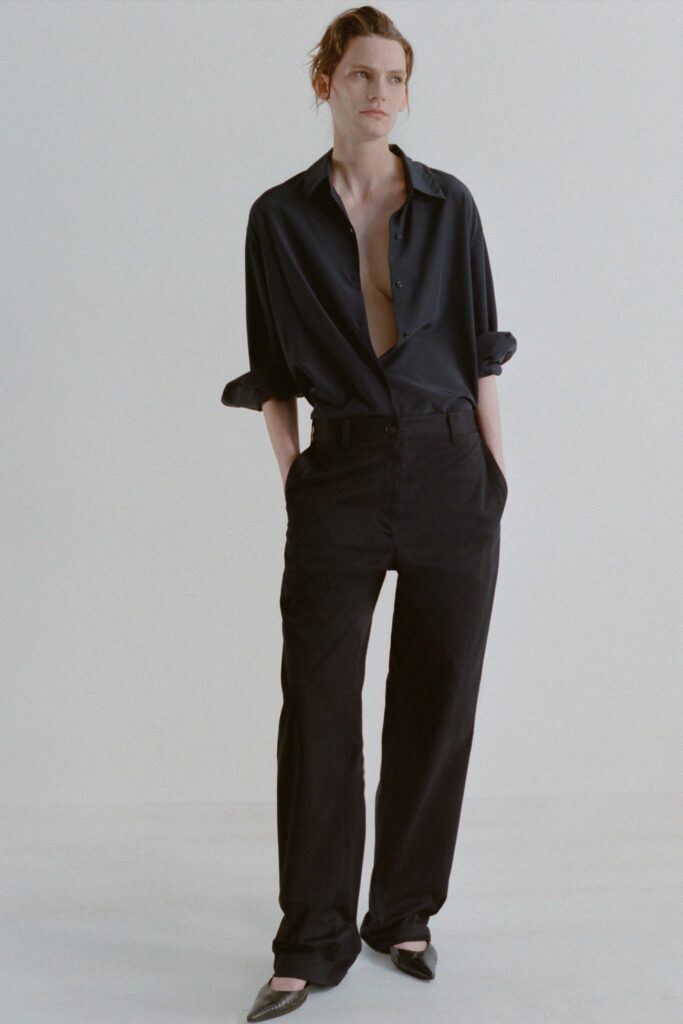 A relaxed black long-sleeve collared shirt paired with straight-leg black pants.