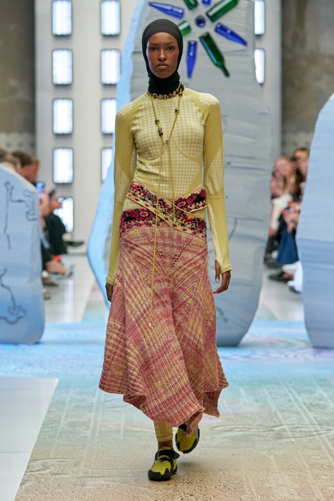 A fitted long-sleeve dress in yellow and pink with an asymmetric layered design.