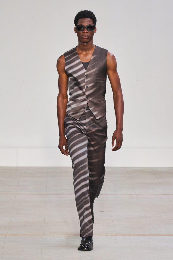 A fitted gray silk vest with a collared design and striped pants.