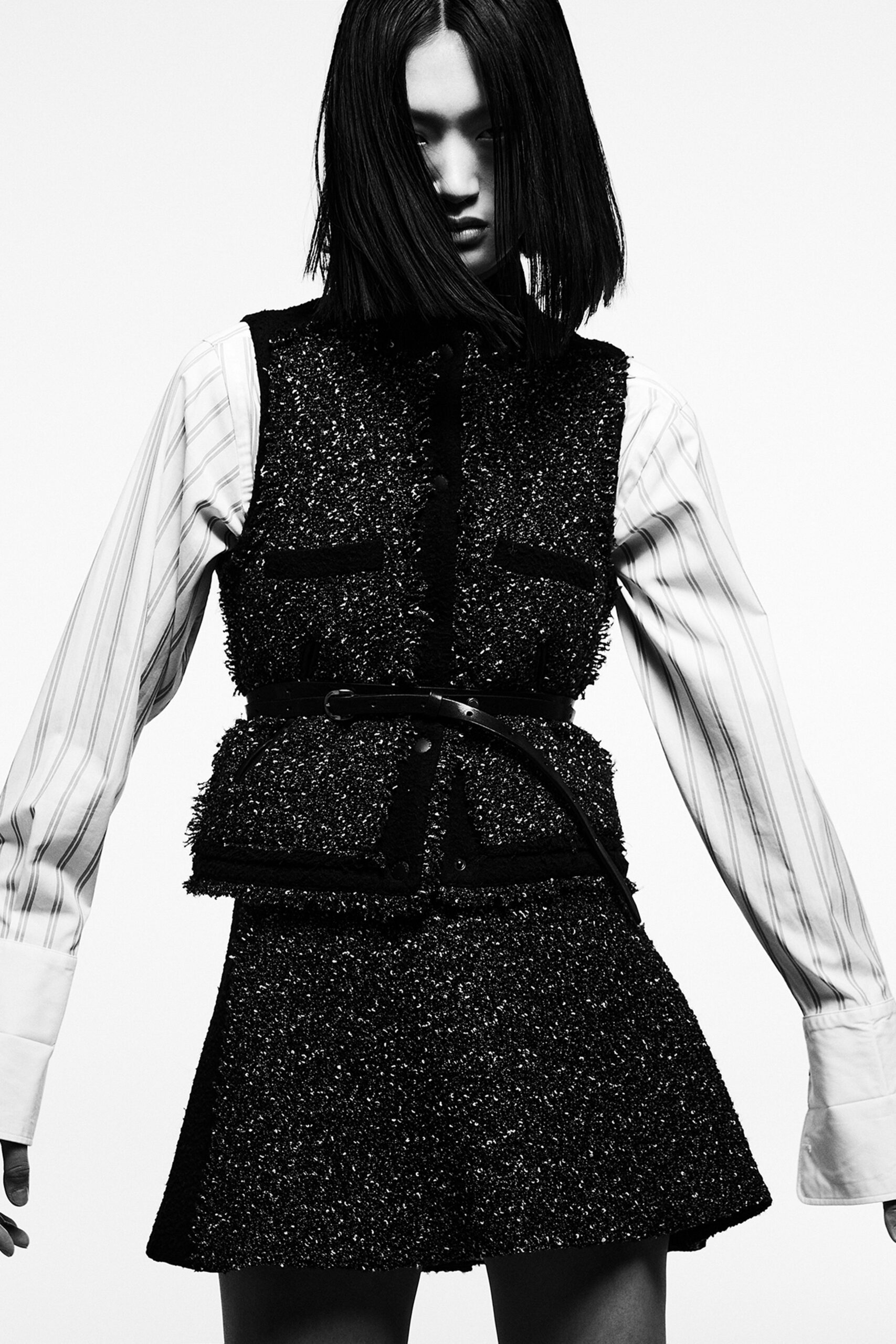 A fitted black and white long-sleeve top with a collared design and a pleated layered skirt.