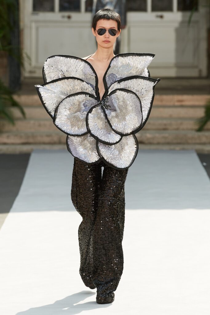 A fitted black sequin sleeveless top with an asymmetric layered design and matching pants.