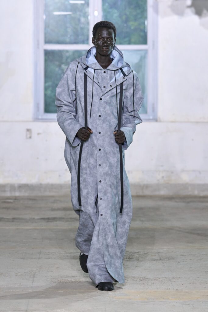 An oversized gray cotton coat with long sleeves and a collared design, featuring button details.