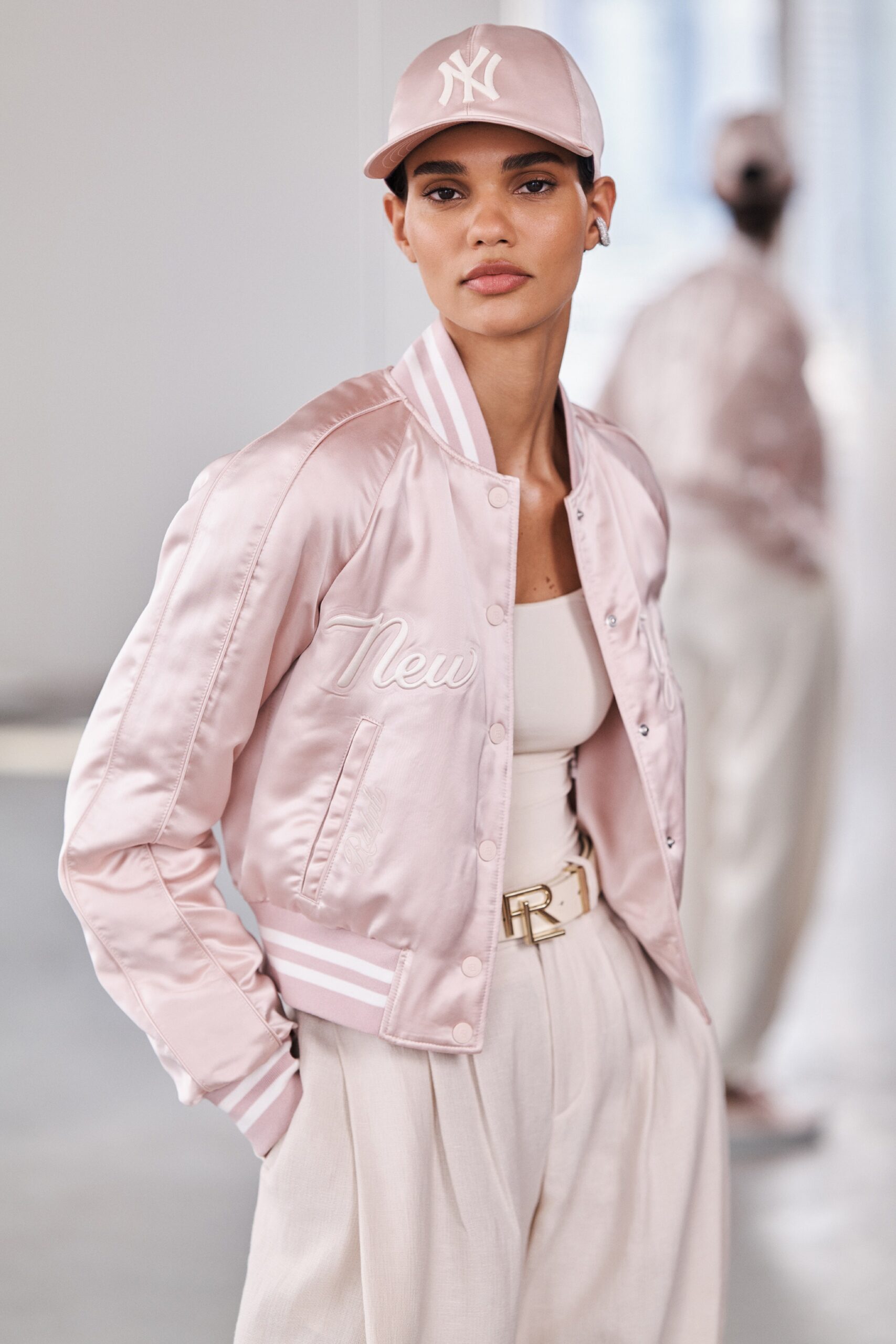 A fitted pink silk jacket with a collared design paired with wide-leg white pants.