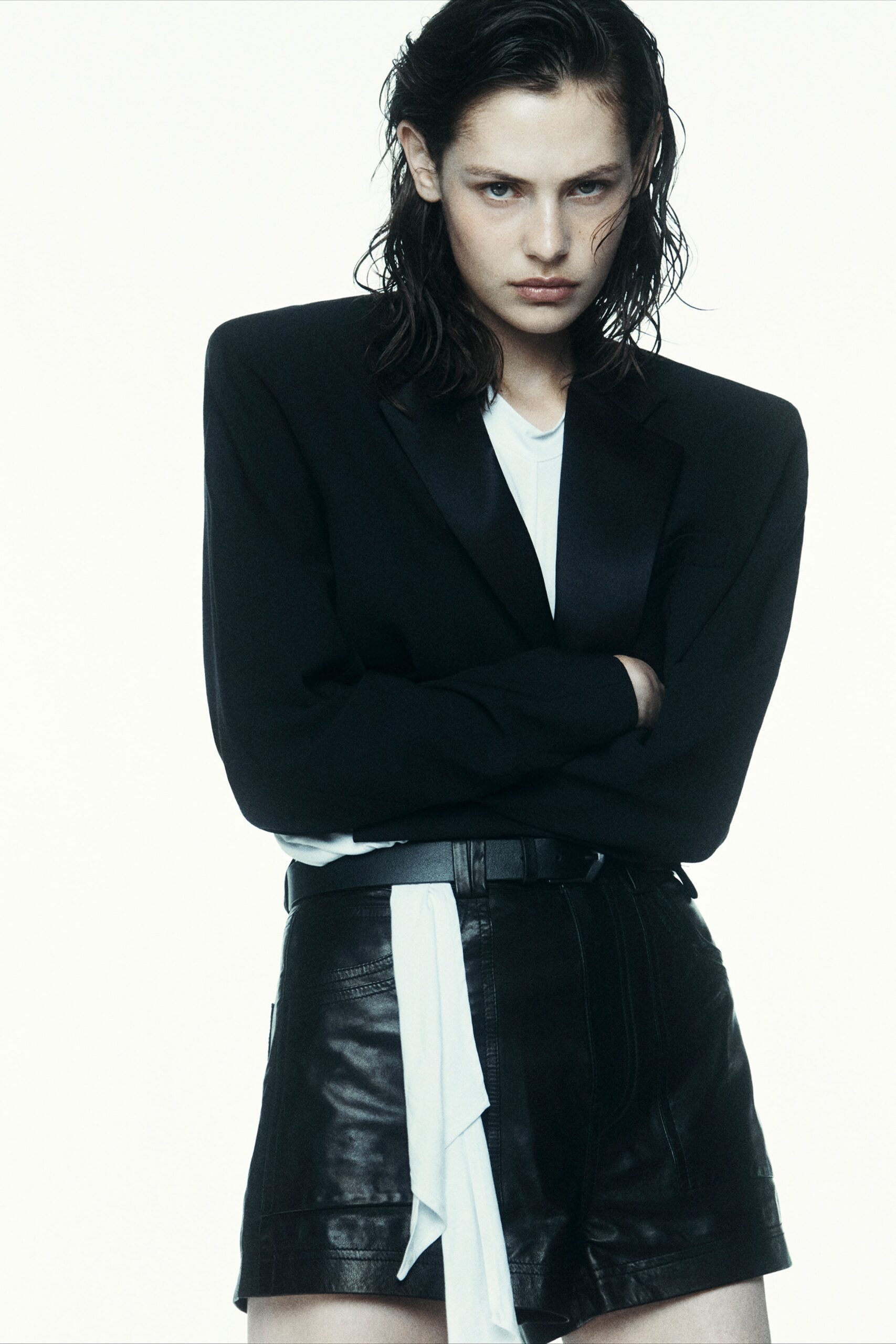 A fitted black leather blazer paired with tailored shorts, featuring an asymmetric design.