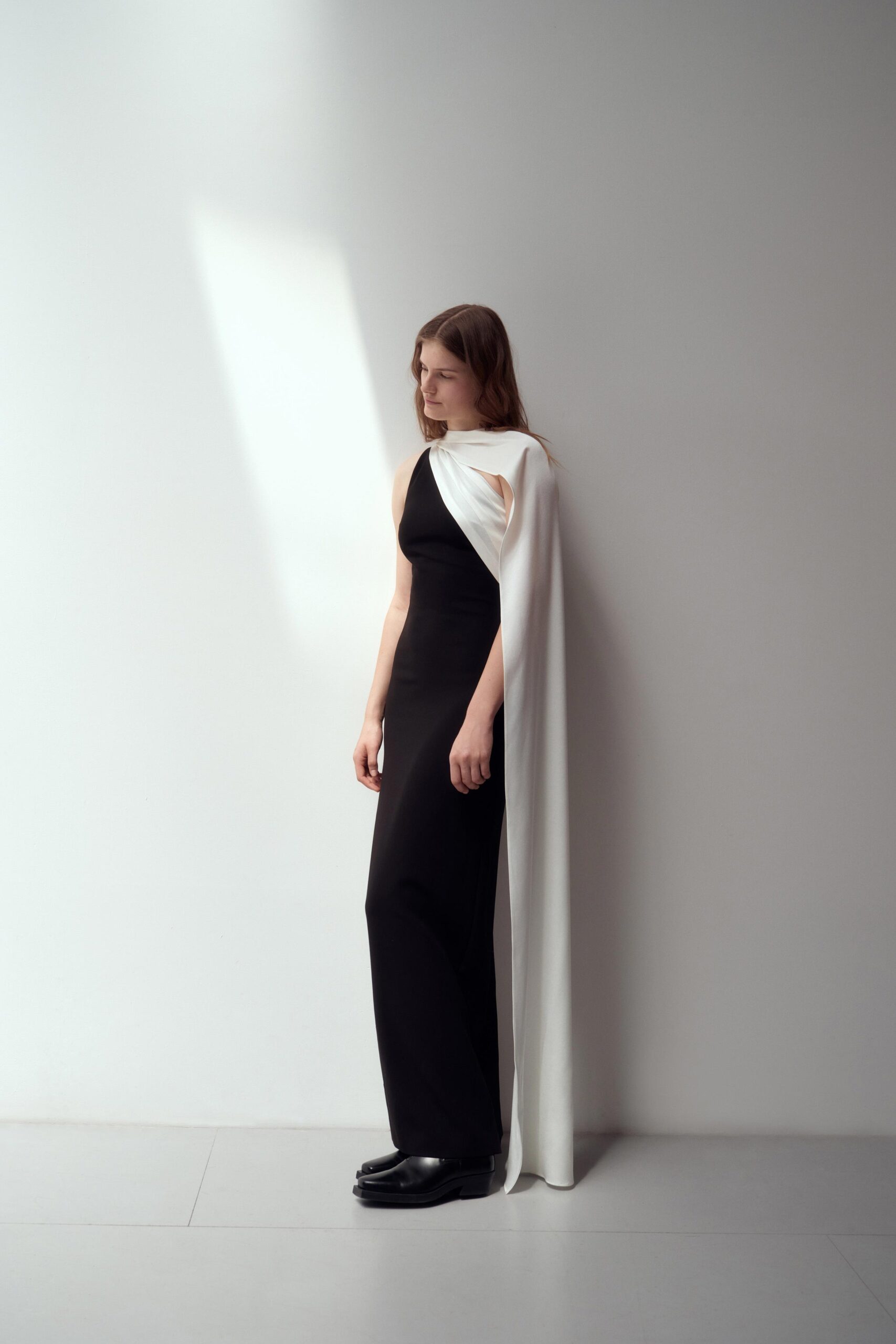 A fitted black dress paired with a flowing white cape, creating a striking contrast.
