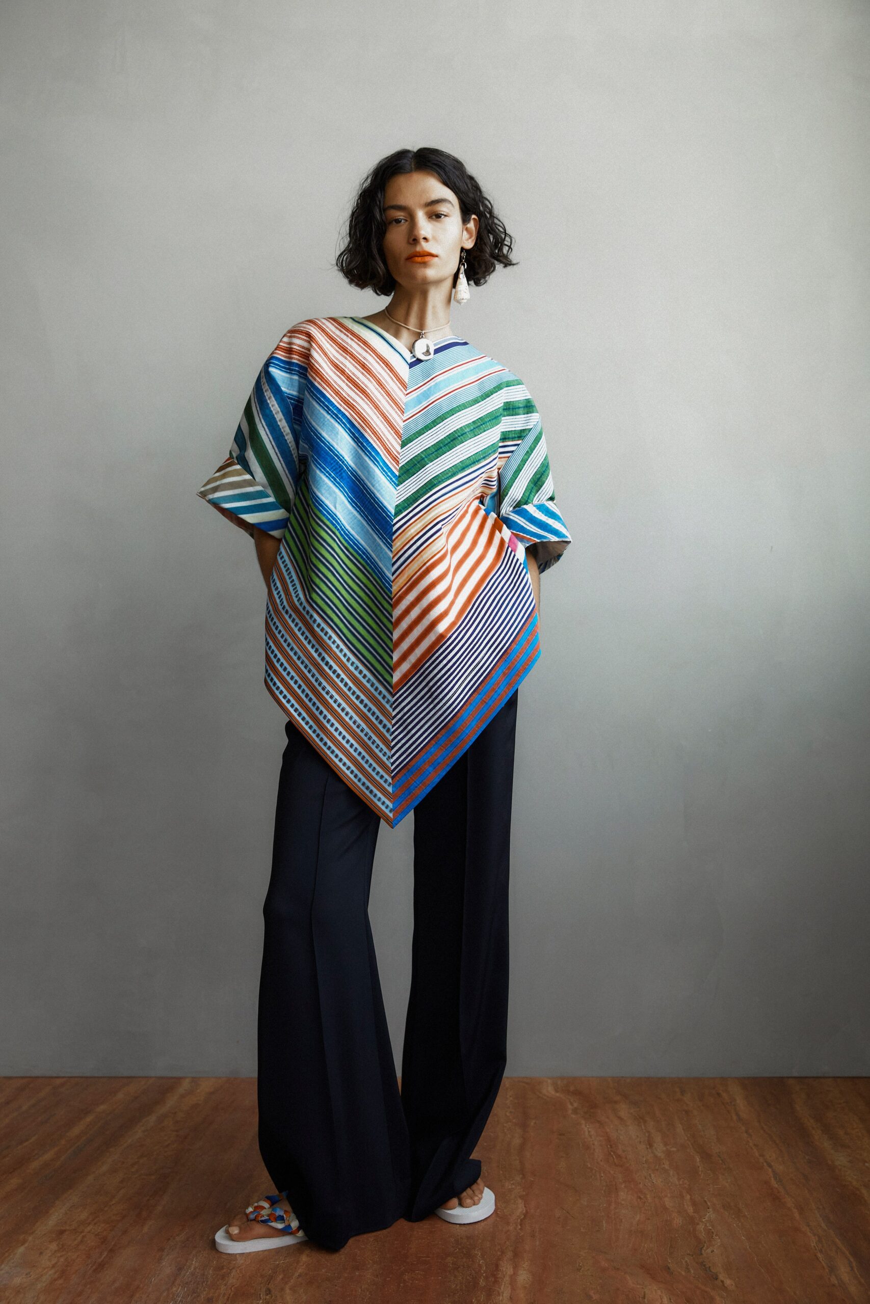 A relaxed multicolor striped top with short sleeves, paired with black pants.