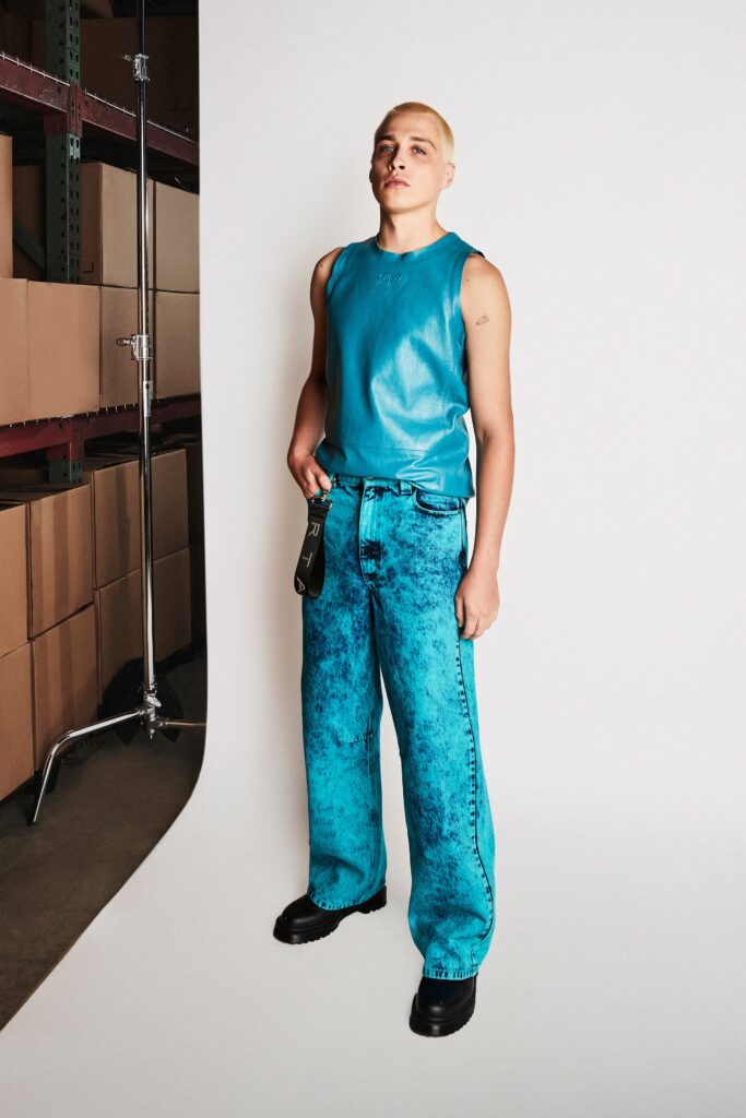 A relaxed blue leather sleeveless top paired with high-waisted wide-leg denim pants.