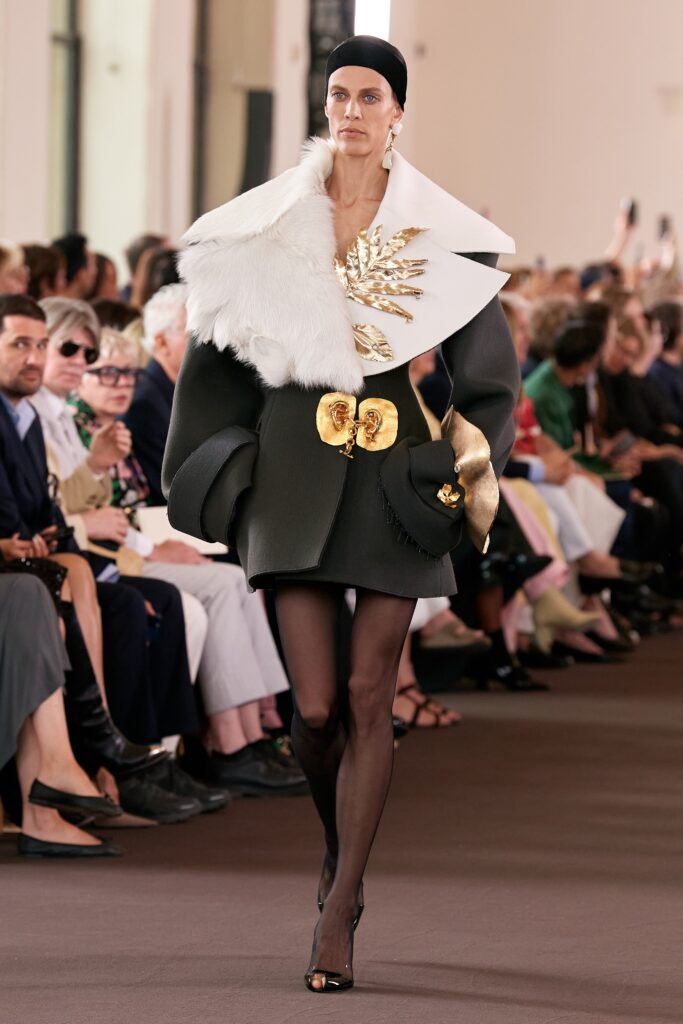 An oversized black and white coat with a layered, asymmetric design and long sleeves.