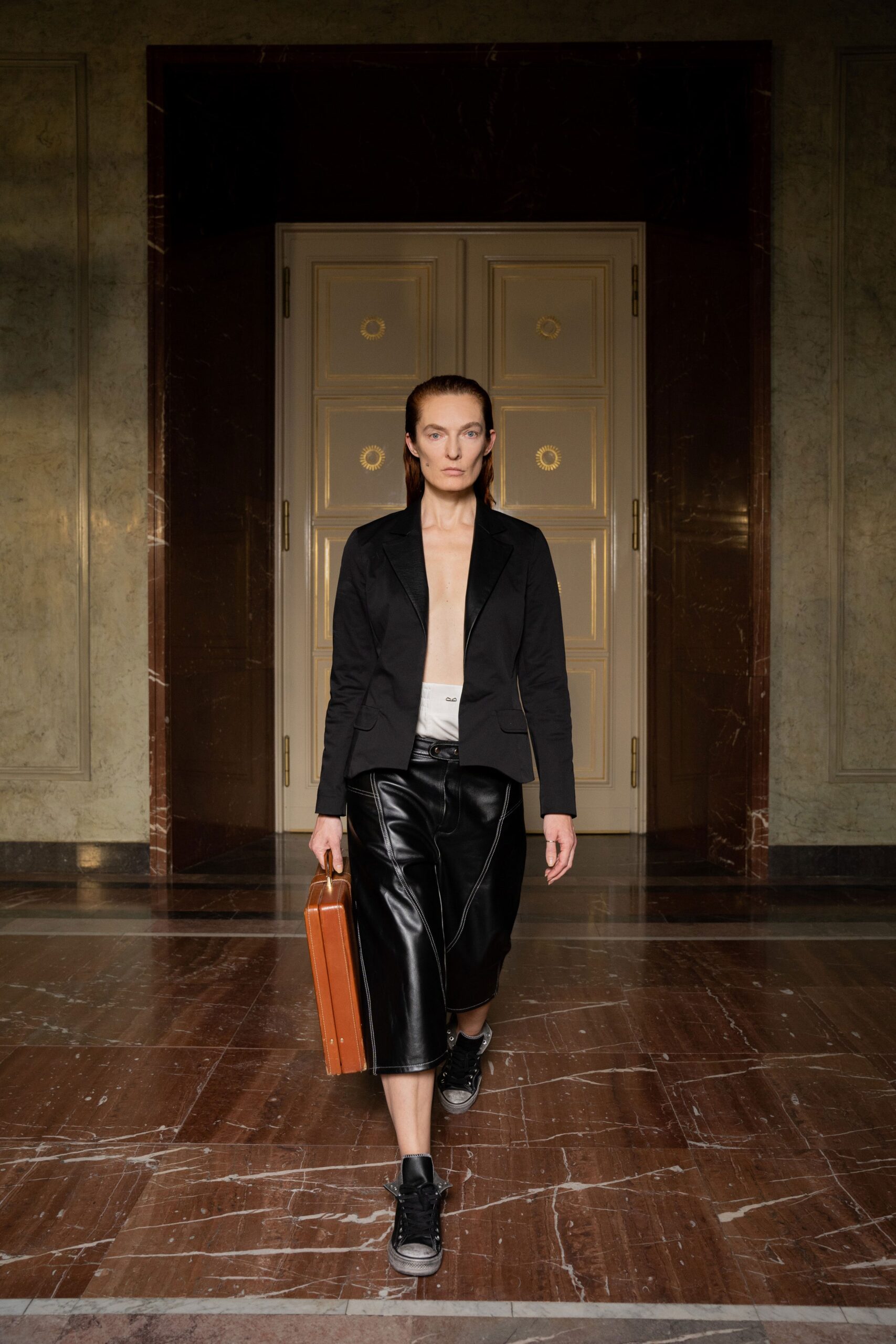 A fitted black leather jacket with long sleeves paired with straight-leg black leather pants.