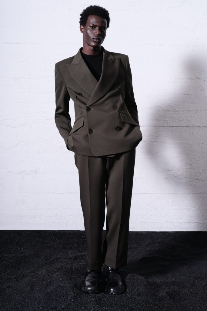 A tailored green wool suit with long sleeves and a collared design, featuring button details.