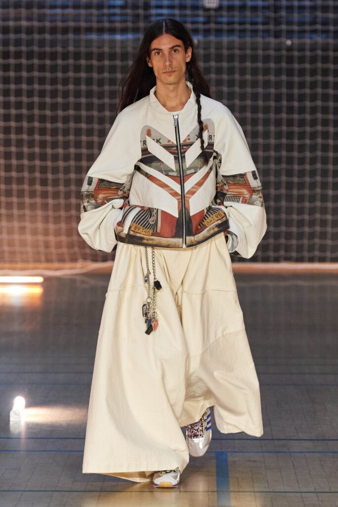 A relaxed white jacket with long sleeves and a collared design paired with a layered skirt.