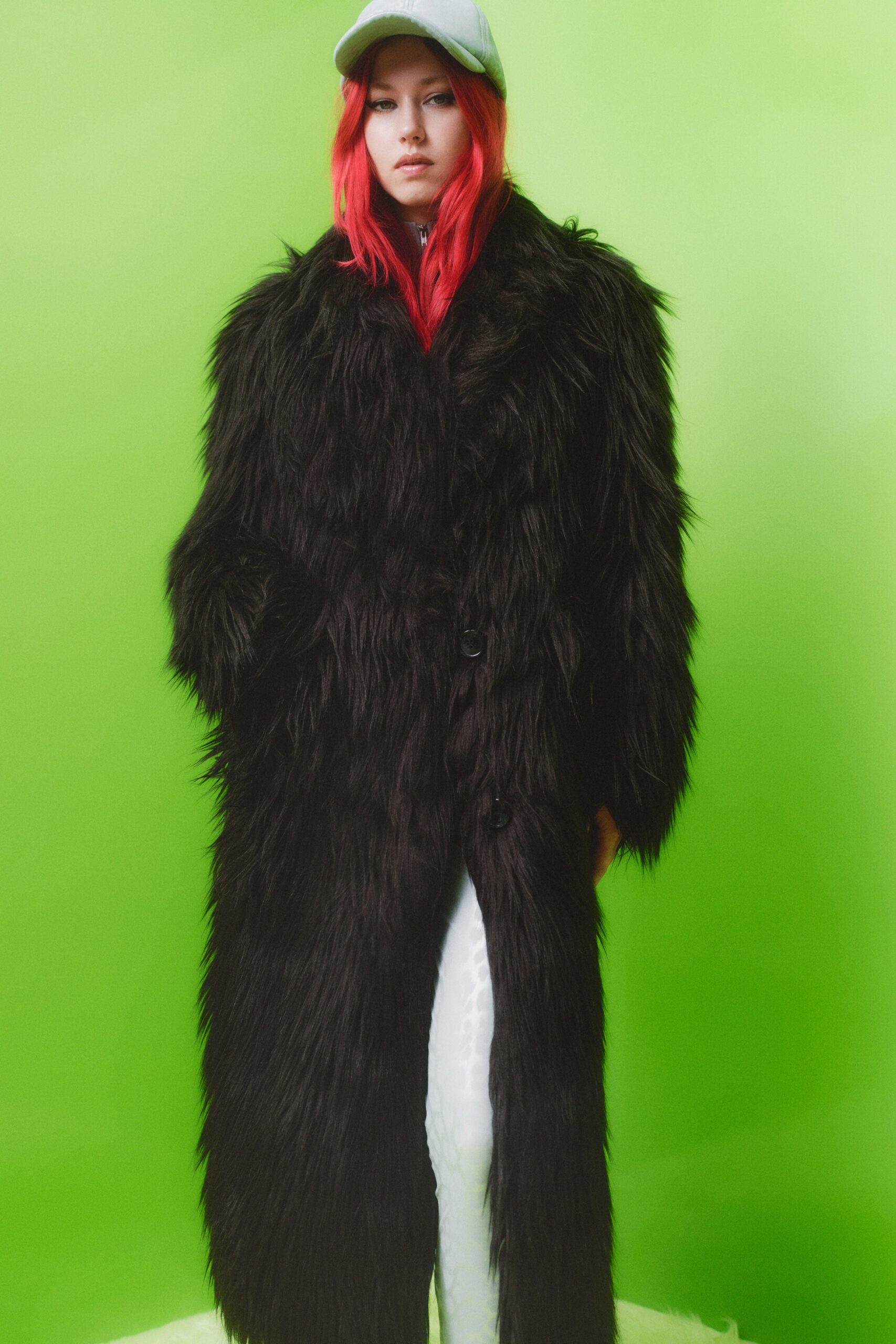 An oversized black fur coat with long sleeves and a collared design, layered for added warmth.
