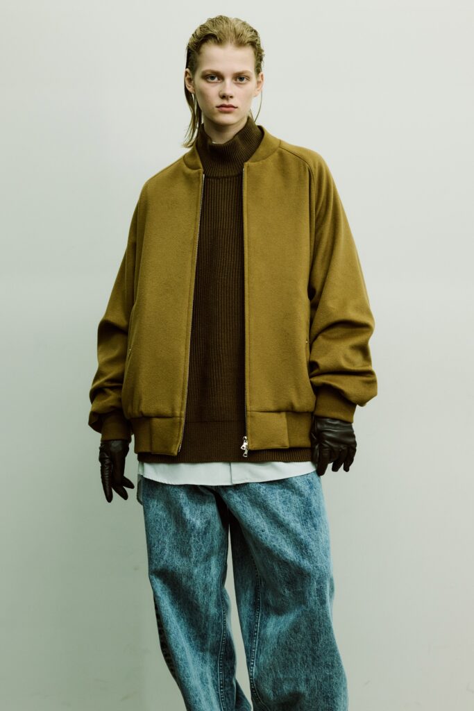 An oversized brown jacket paired with blue denim pants, creating a relaxed yet stylish look.
