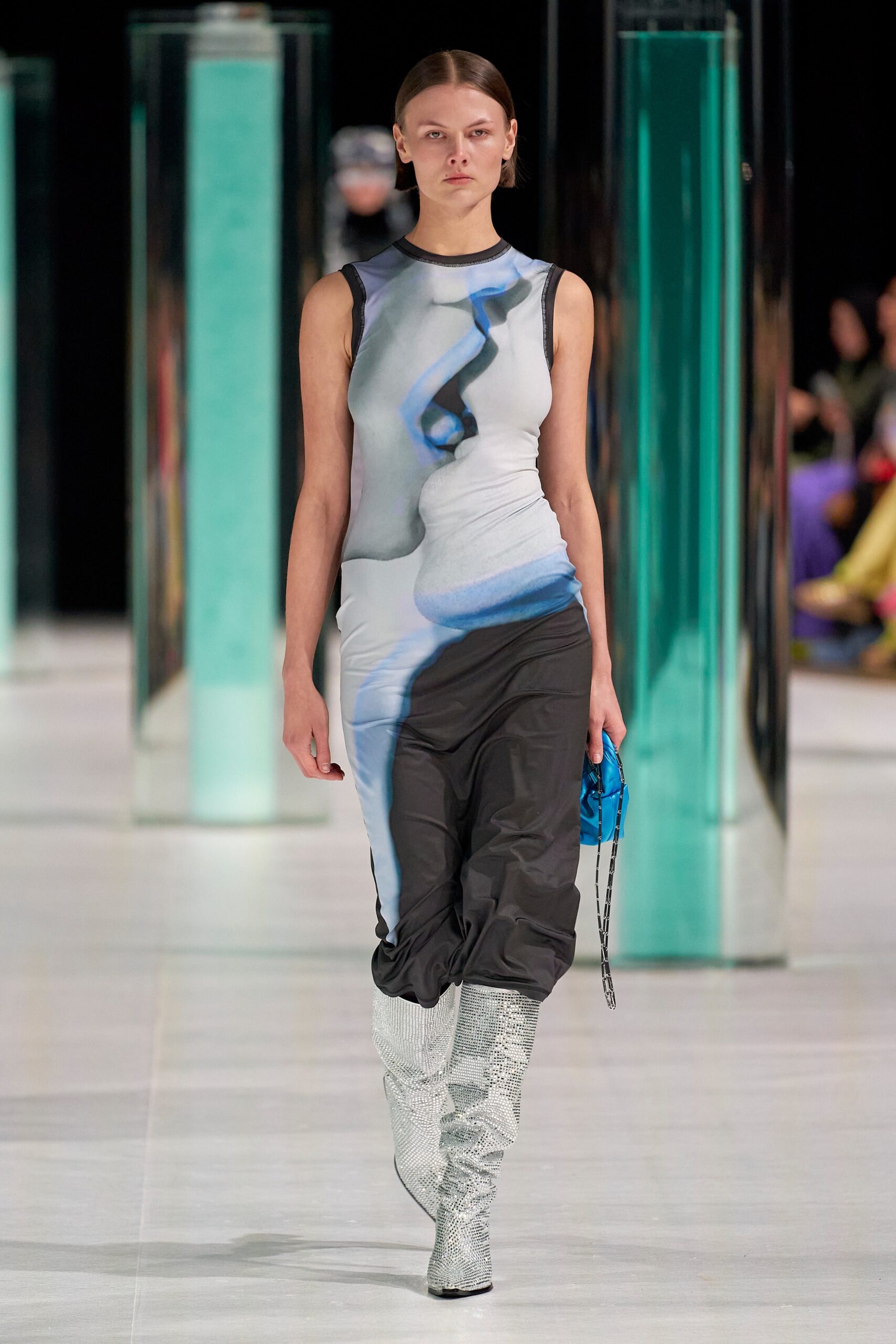 A fitted sleeveless dress in black and blue with a high-neck and printed design.