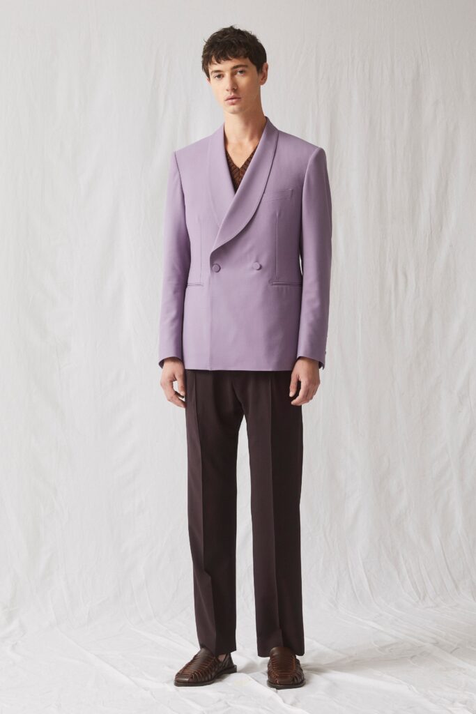 A tailored purple double-breasted blazer paired with straight-leg brown trousers.