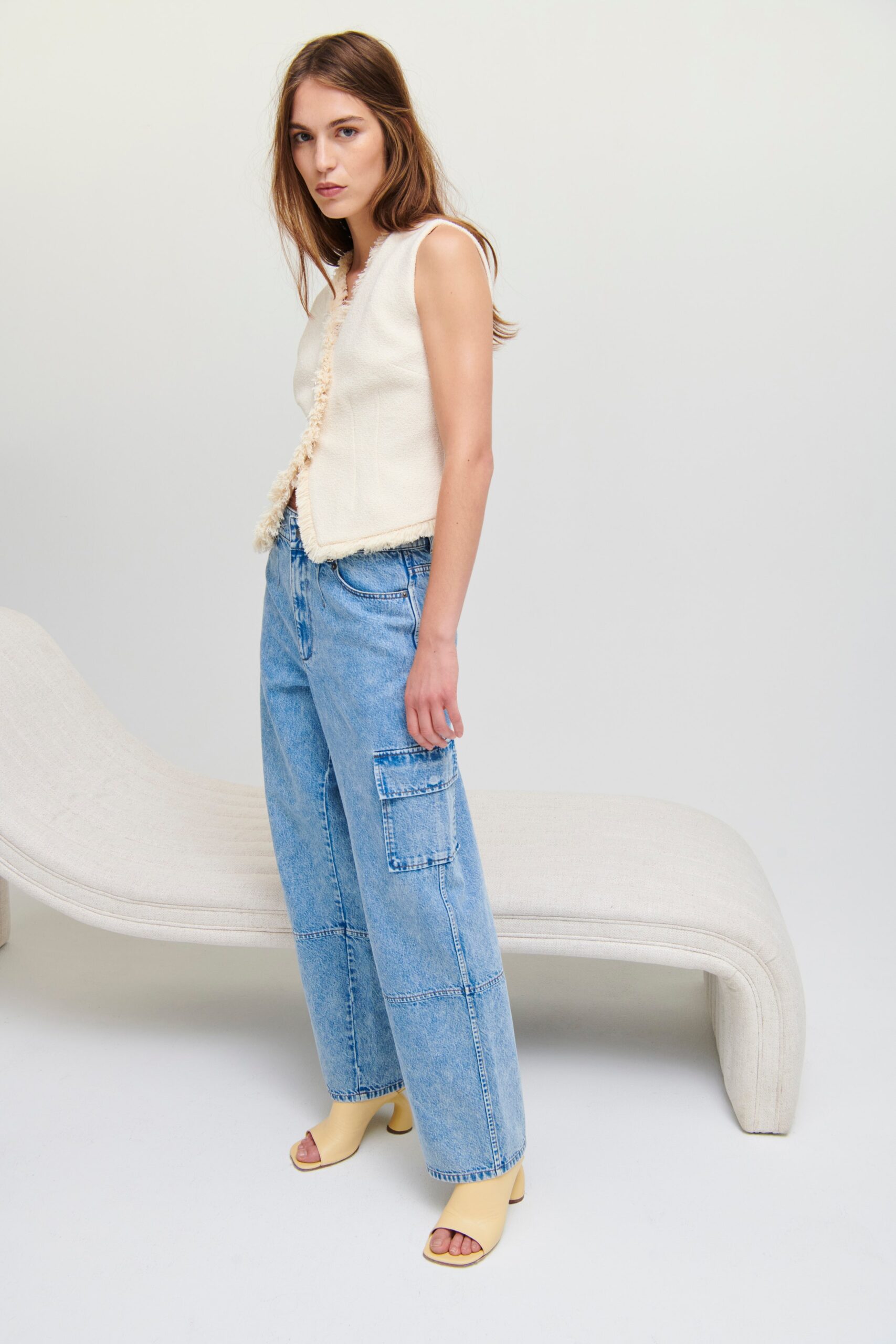 A relaxed beige sleeveless top paired with wide-leg blue denim pants.