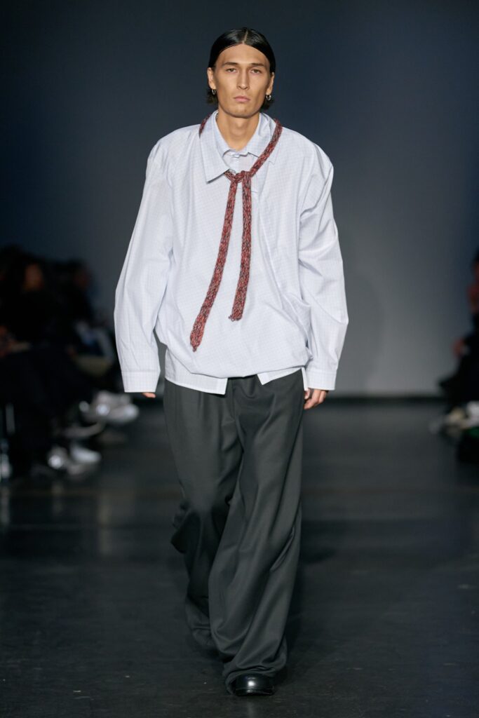 A relaxed long-sleeve white shirt with a collar paired with wide-leg gray pants.