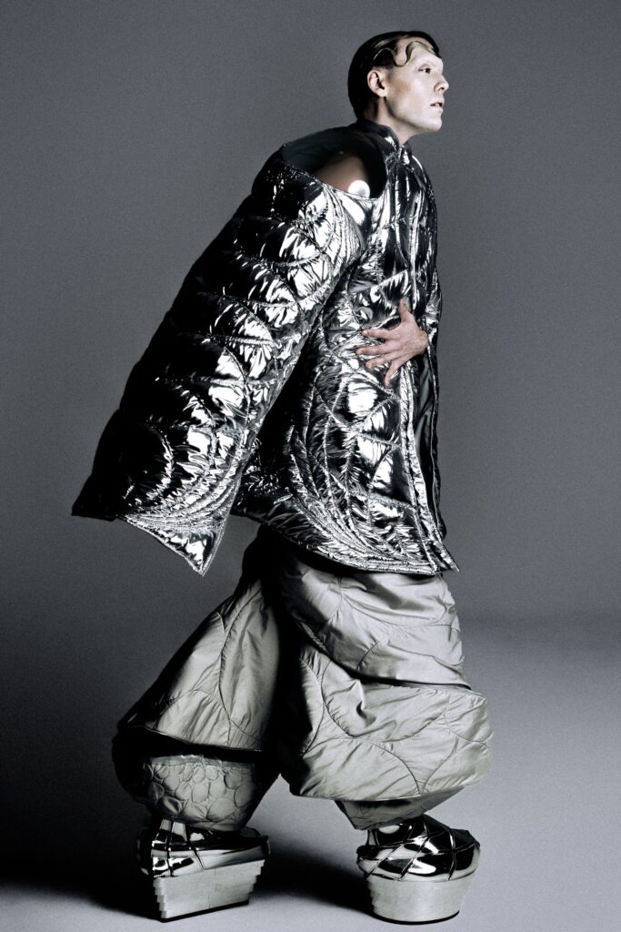 A relaxed silver metallic jacket with long sleeves paired with wide-leg gray pants.