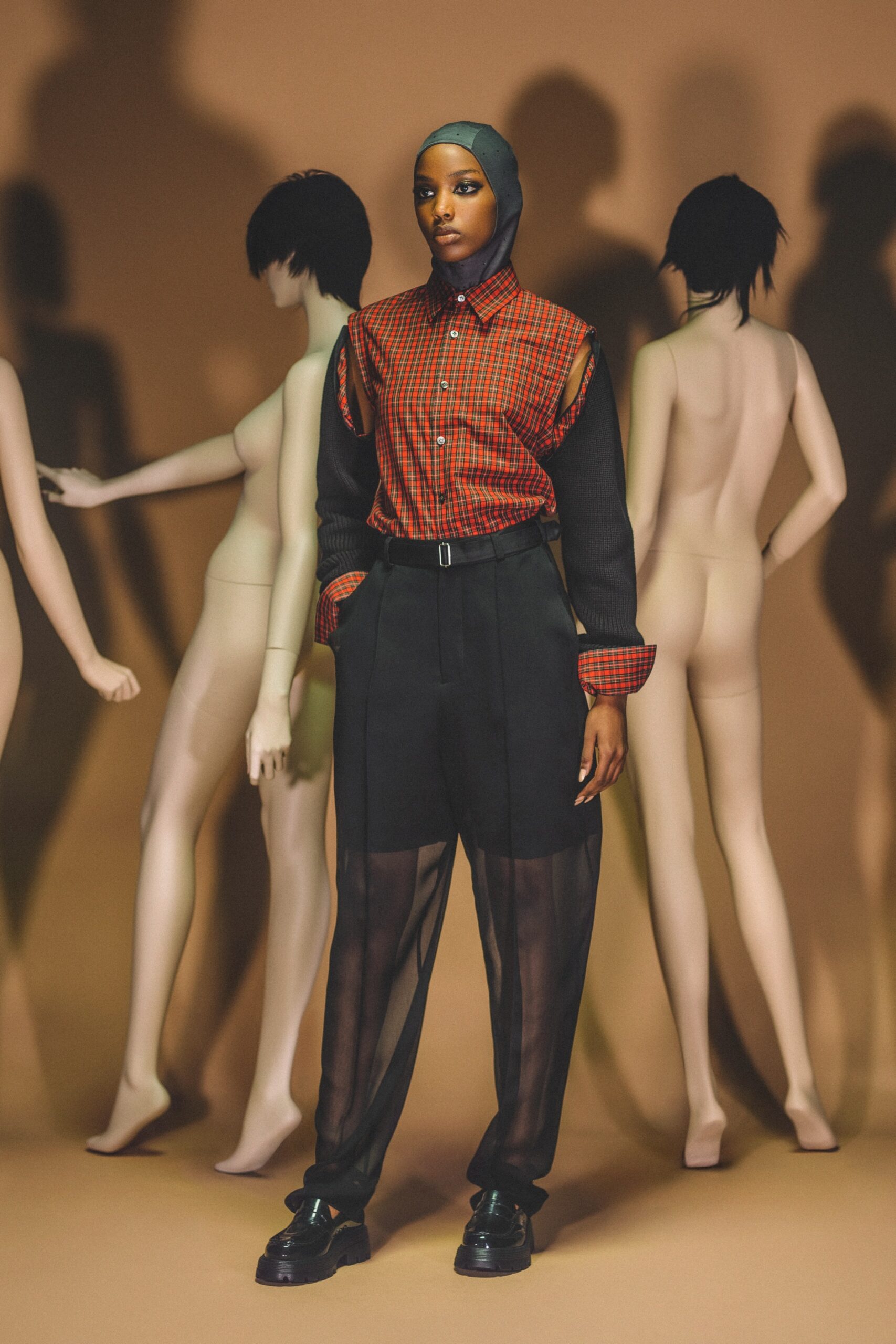 A relaxed black and red collared shirt with long sleeves paired with sheer black pants.