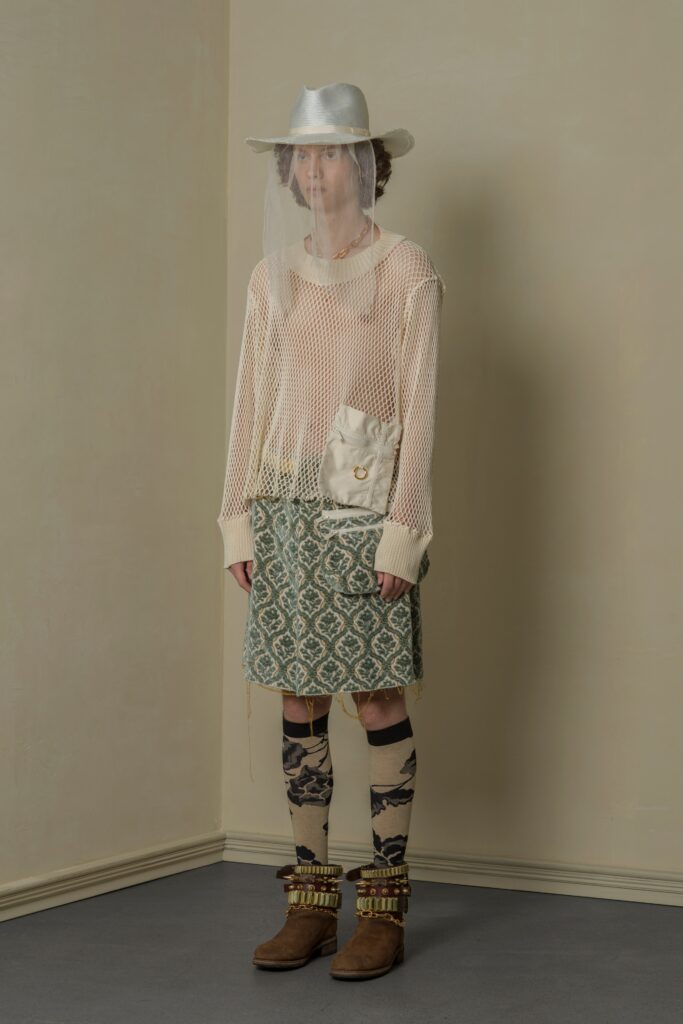 A relaxed beige knit top paired with a layered printed skirt.
