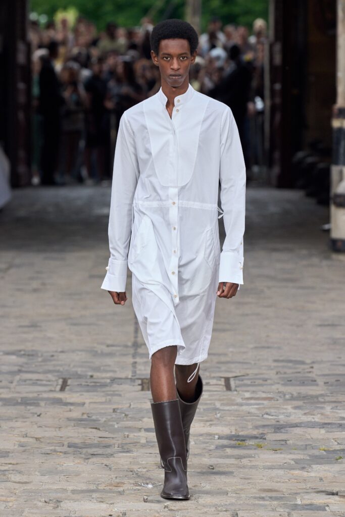 A relaxed white cotton shirt-dress with long sleeves and a collared neckline, featuring button details.