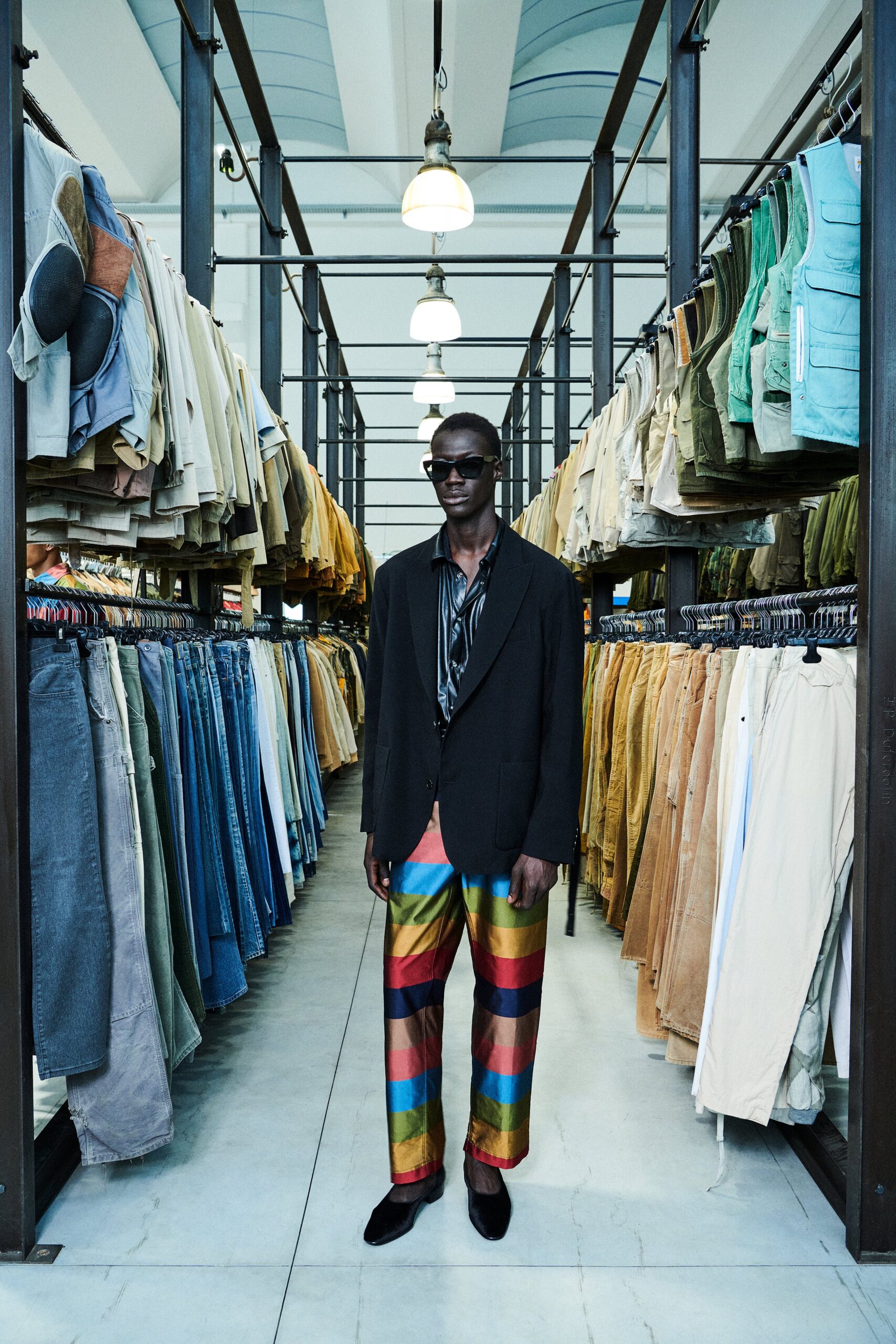 A relaxed black blazer paired with multicolor striped pants for a bold fashion statement.