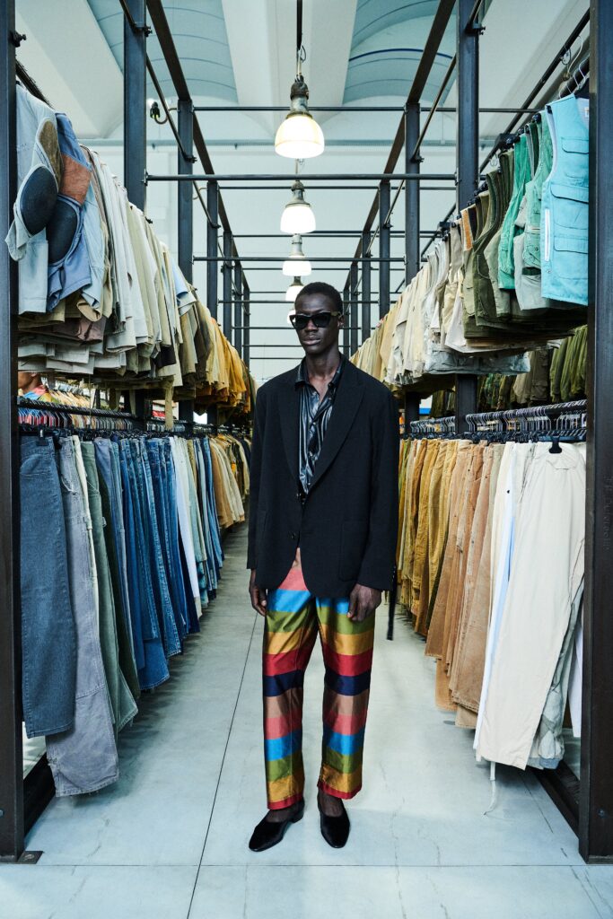 A relaxed black blazer paired with multicolor striped pants, featuring a collared design.