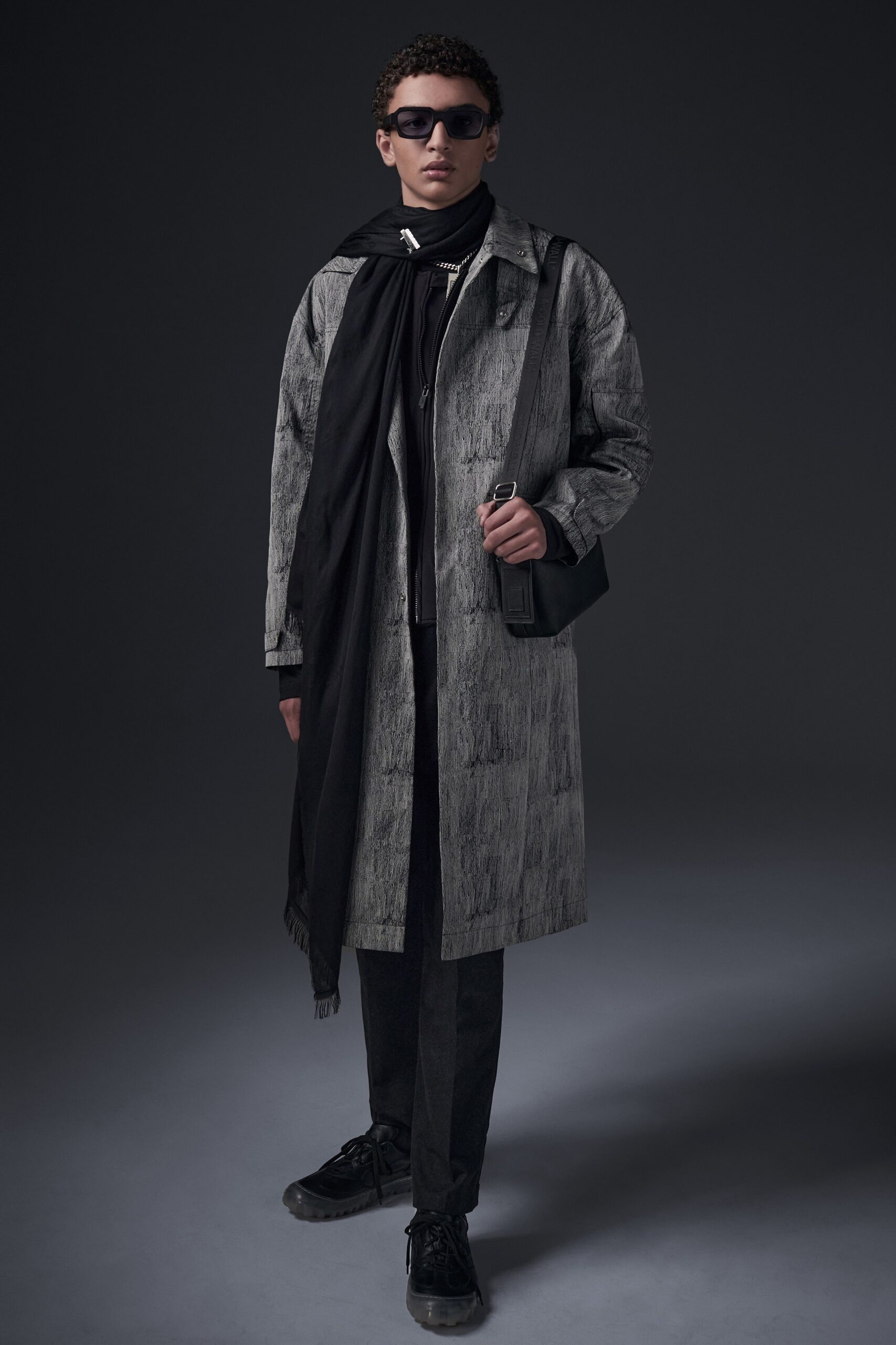 This relaxed coat in a muted gray features an asymmetric design that adds depth to its silhouette. Paired with matching pants, the ensemble creates a cohesive look that balances structure with effortless layering.