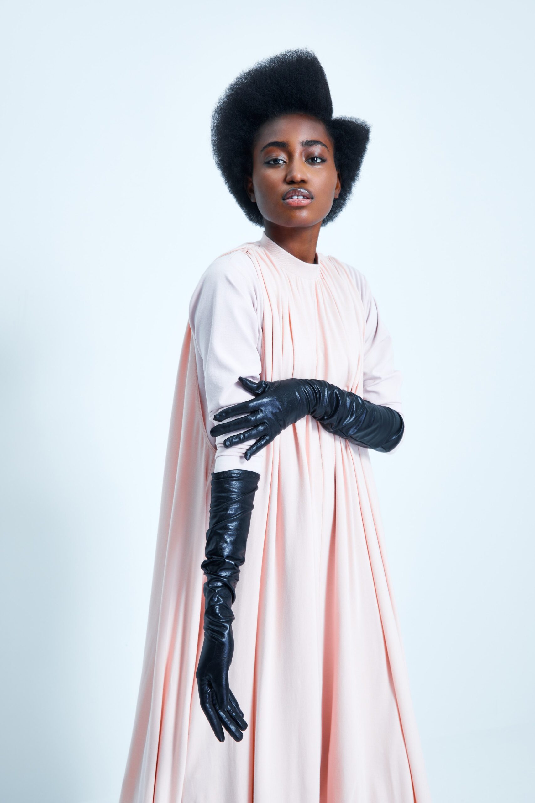 This relaxed dress features a soft pink hue and a high-neck design, creating a gentle drape that enhances its fluid silhouette. The pleated texture adds depth and movement, allowing for an effortless flow that captivates with each step.