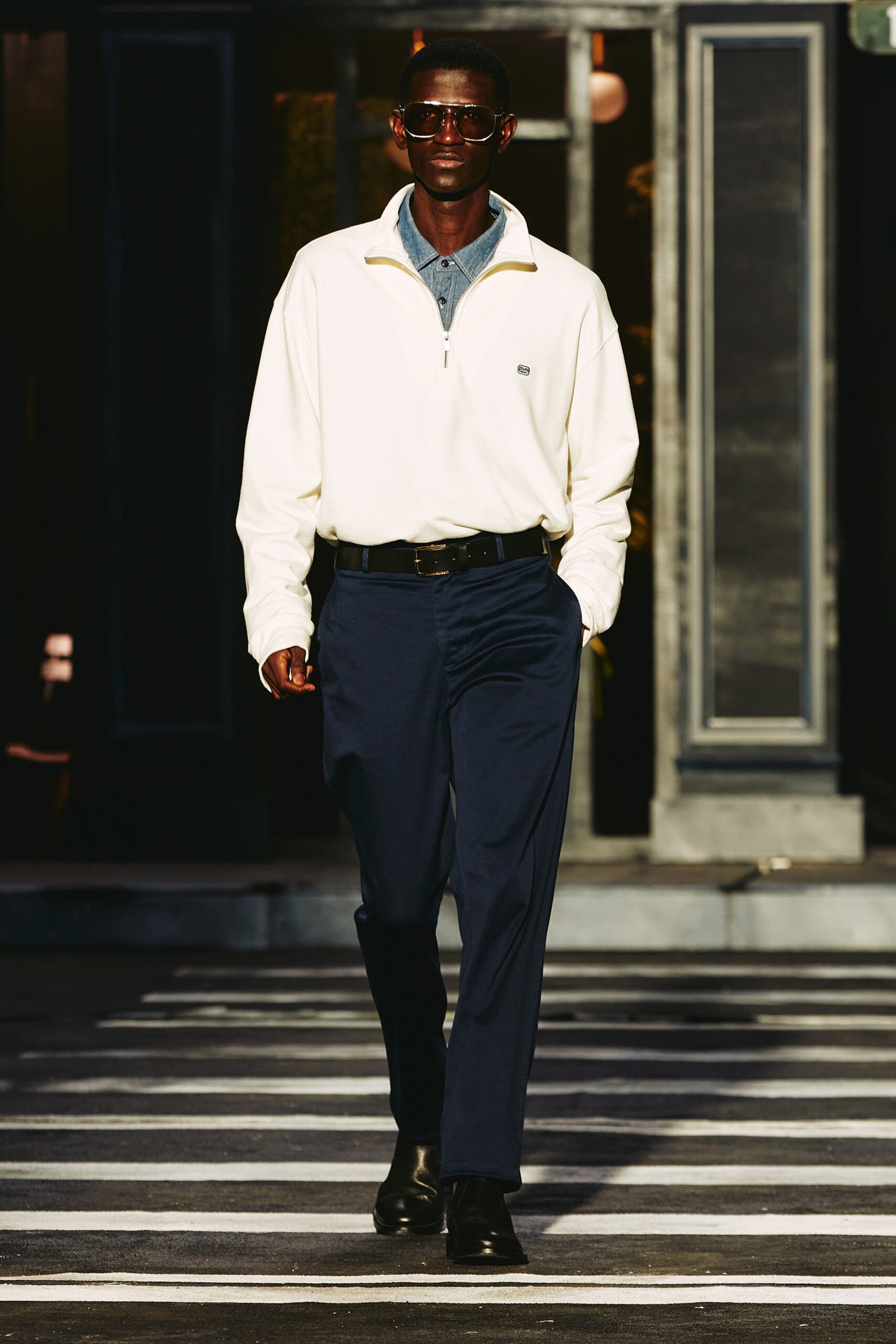 A relaxed white cotton jacket with a collared neckline paired with navy pants.