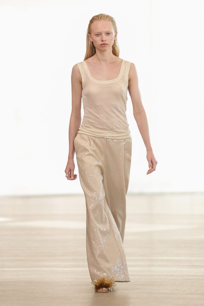 A relaxed beige sleeveless top paired with wide-leg sequined pants for a chic look.