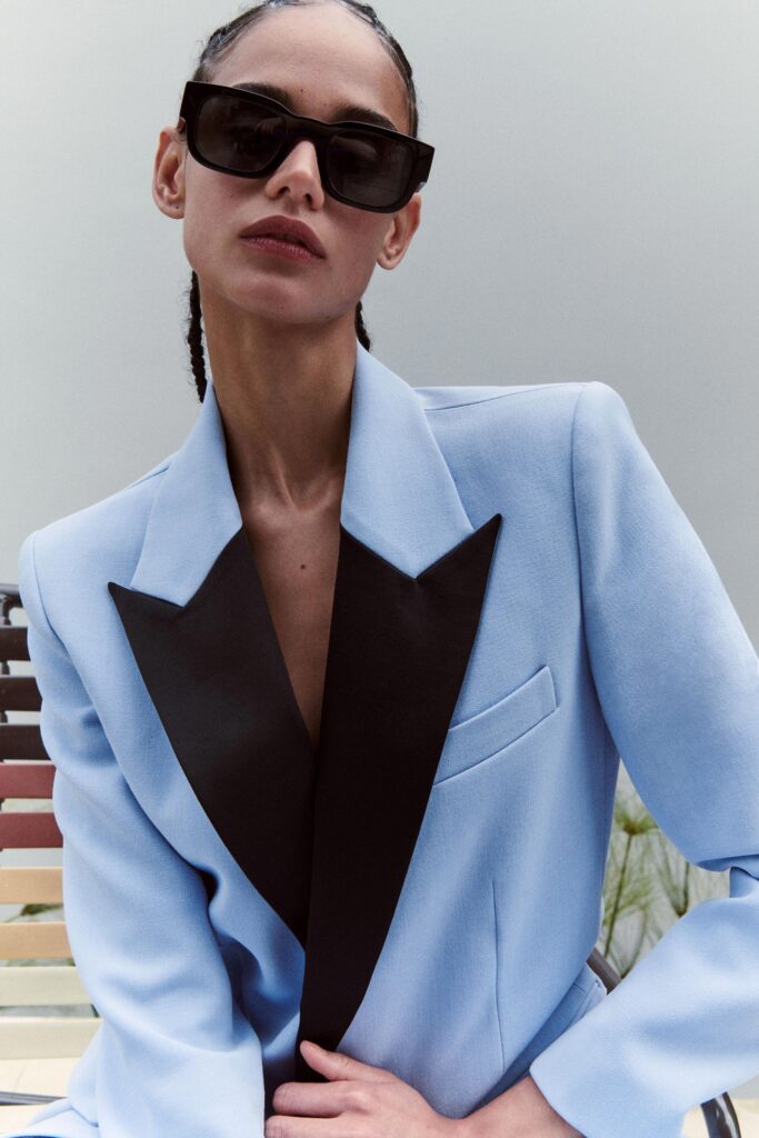 A fitted blue blazer with black lapels, long sleeves, and a structured design.