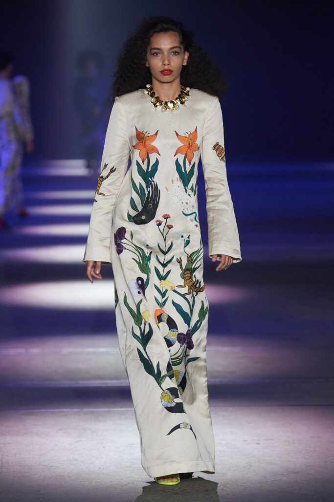 A fitted white silk dress with long sleeves, high neckline, and intricate embroidery.