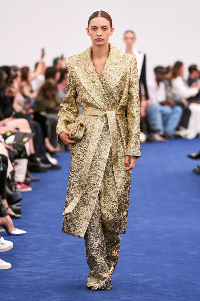 A fitted gold silk coat with long sleeves, a collared neckline, and textured design details.