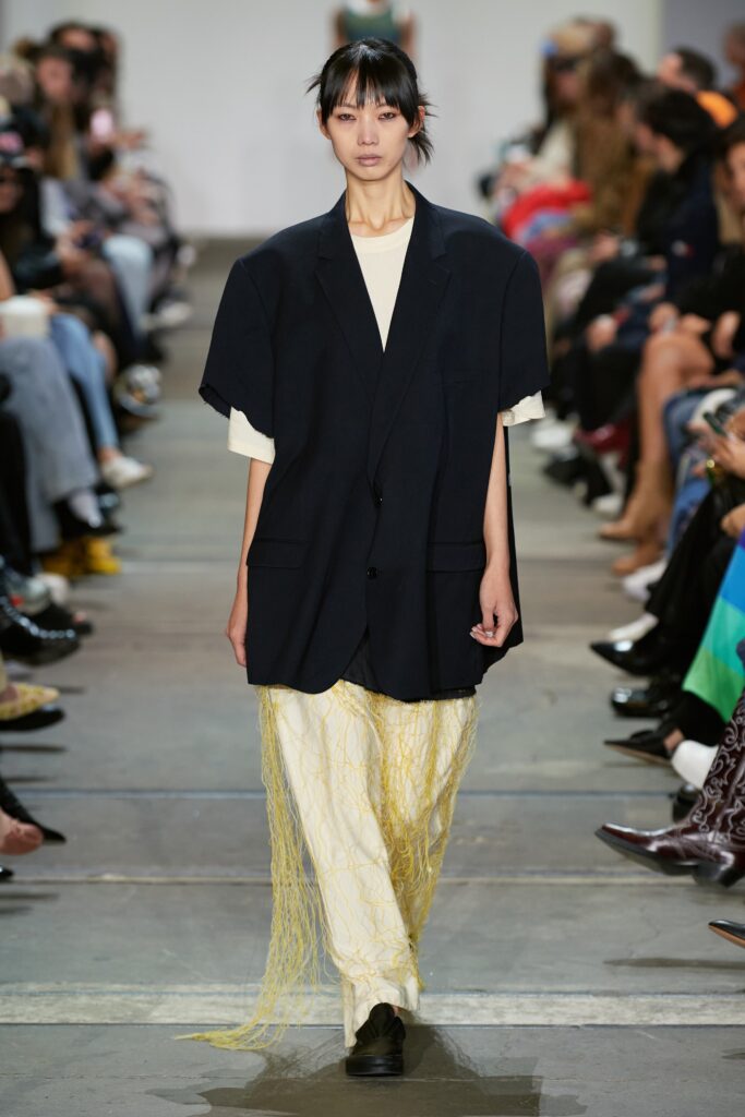 An oversized black jacket paired with layered white and yellow pants for a striking runway look.