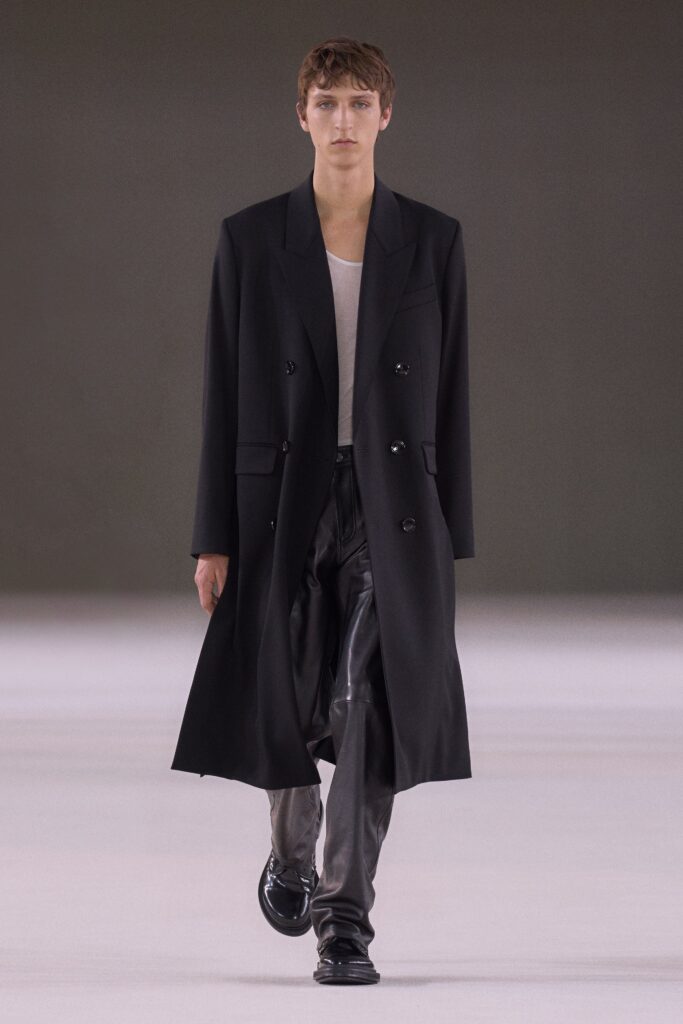 A relaxed black leather coat paired with matching pants, featuring a collared design and buttoned details.