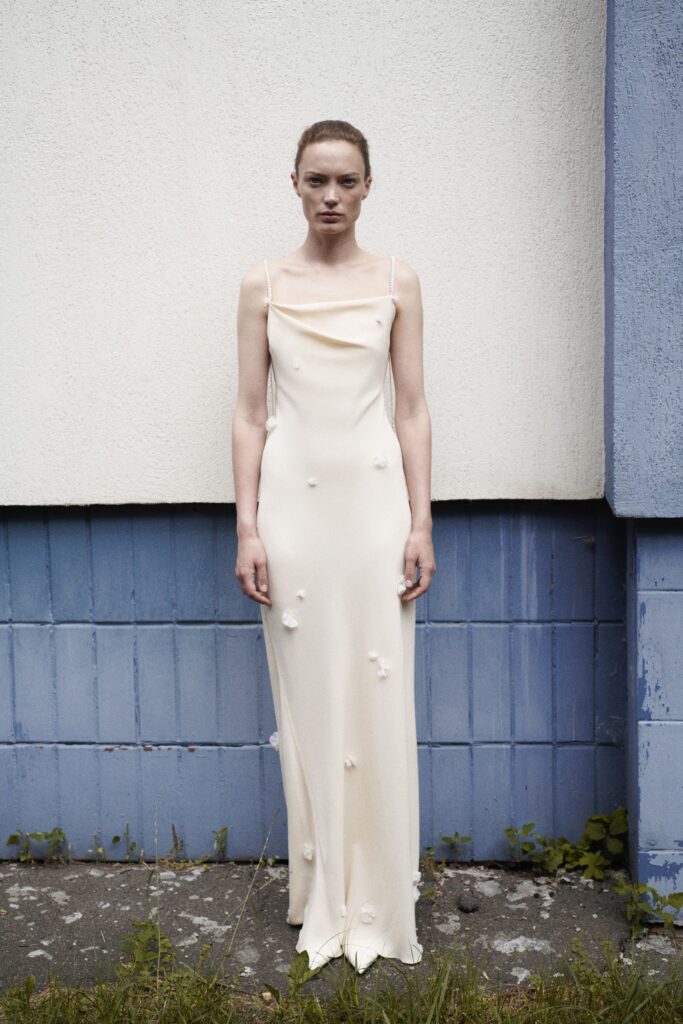 A fitted cream silk sleeveless dress with a draped design and V-neckline.
