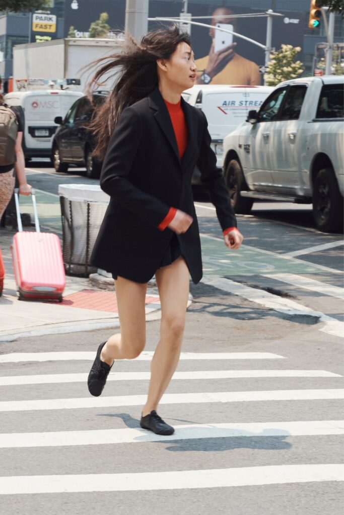 A fitted black blazer worn over a red dress with a V-neckline and asymmetric design.