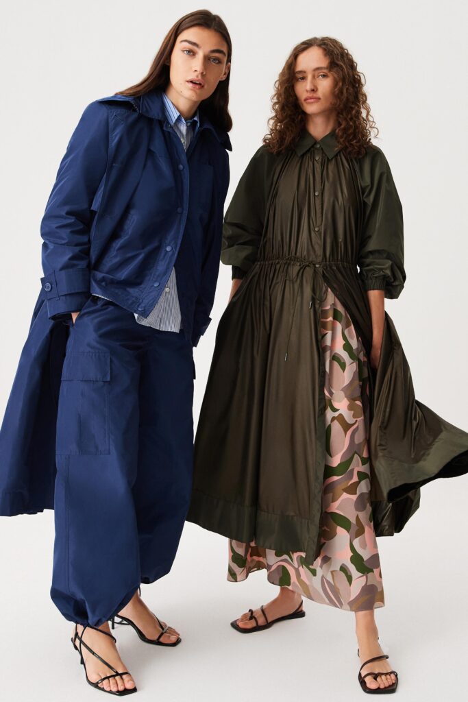 A relaxed blue jacket paired with a long-sleeve green dress featuring a layered and printed design.