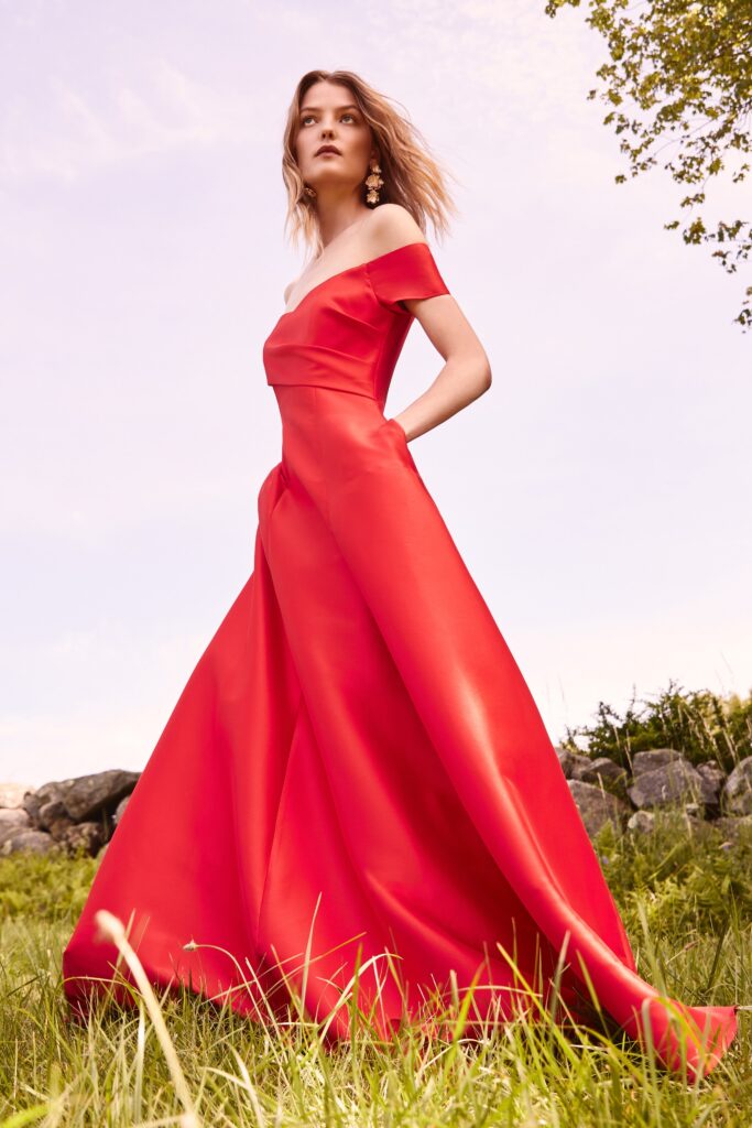 A fitted red silk off-shoulder gown with an A-line silhouette.