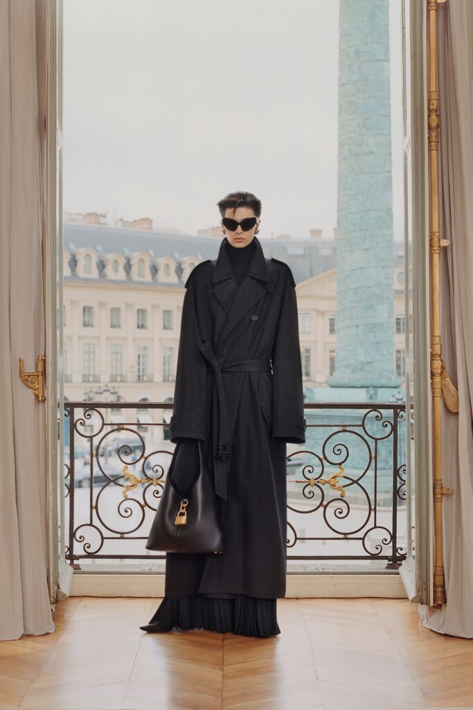A fitted black wool coat layered over a dress with long sleeves and a collared design.