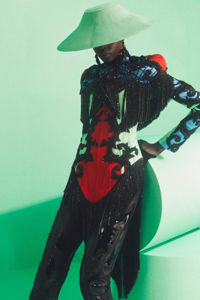 fringed black and red jumpsuit with green hat