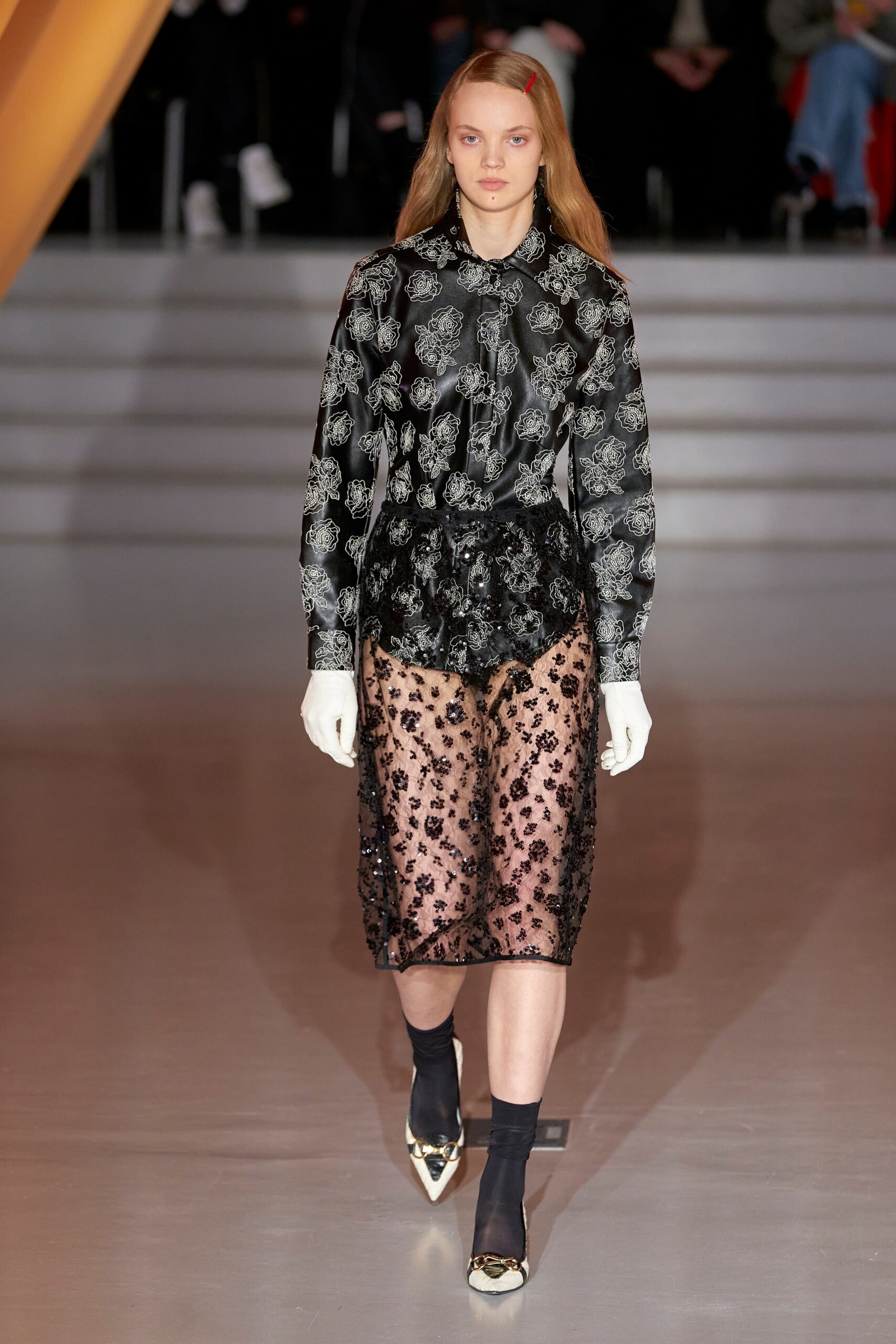 A fitted black silk dress with long sleeves, a collared neckline, and sheer embroidered details.