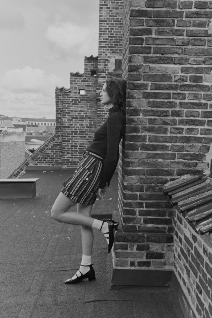 A fitted black long-sleeve top paired with a pleated striped skirt.