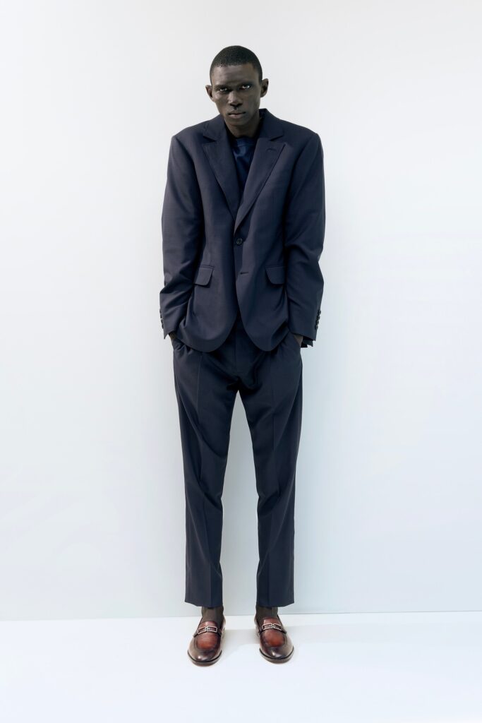 A tailored navy suit with long sleeves and a collared shirt, featuring straight-leg trousers.