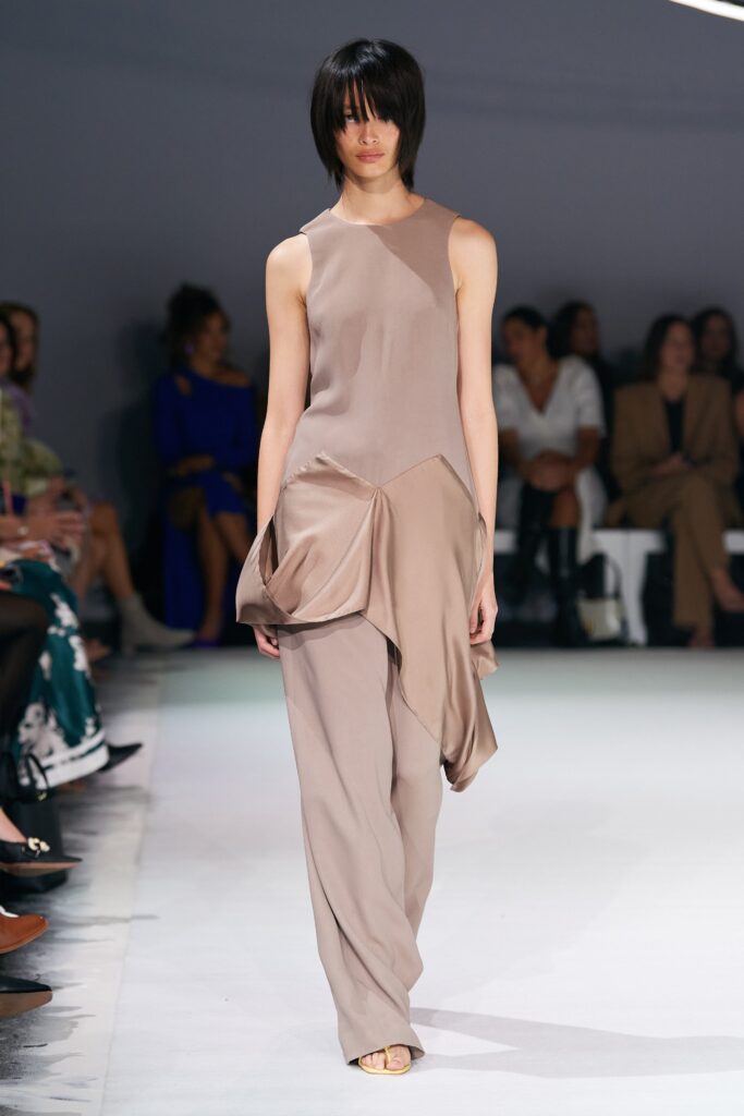 A relaxed beige silk sleeveless dress with a high neckline and draped design.
