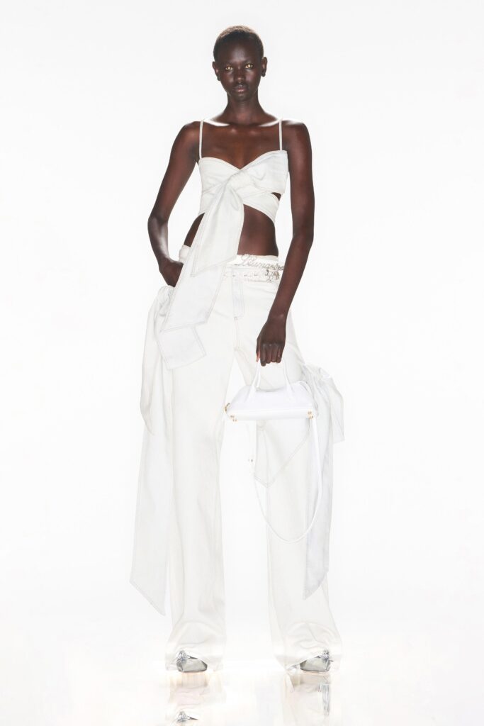 A relaxed white sleeveless top with asymmetric details paired with layered pants.