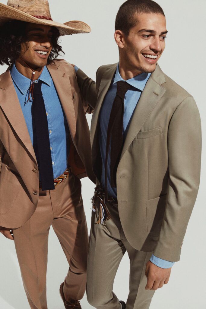 A tailored beige suit paired with a blue collared shirt and buttoned details.