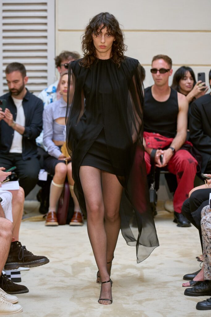 A fitted black silk sleeveless dress with a high neckline and asymmetric design.