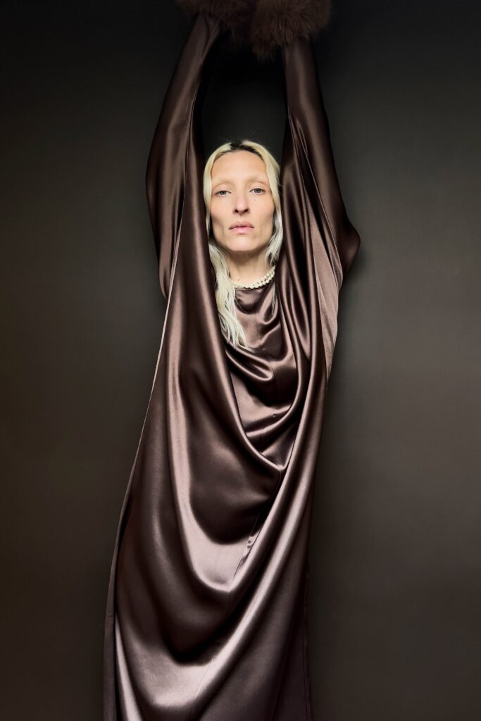 A relaxed brown silk sleeveless dress with a high neckline and draped design.
